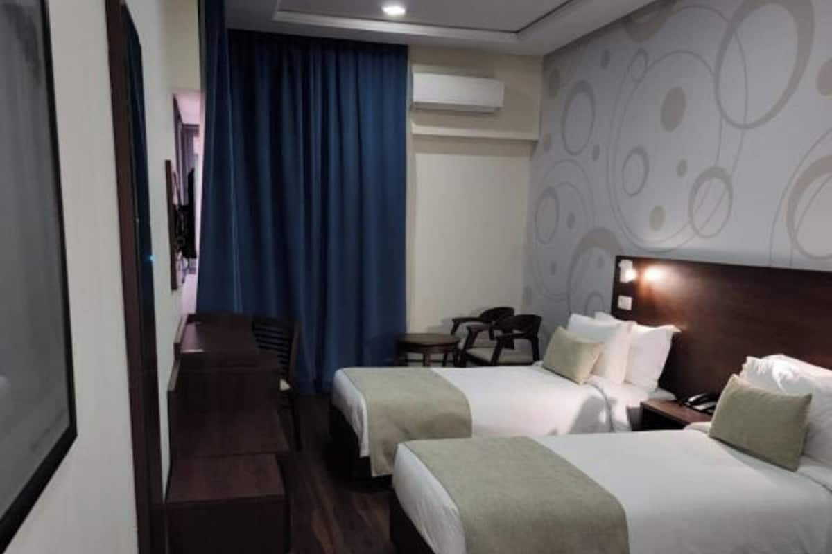 Une chambre d’hôtel avec deux lits, un bureau et une chaise.