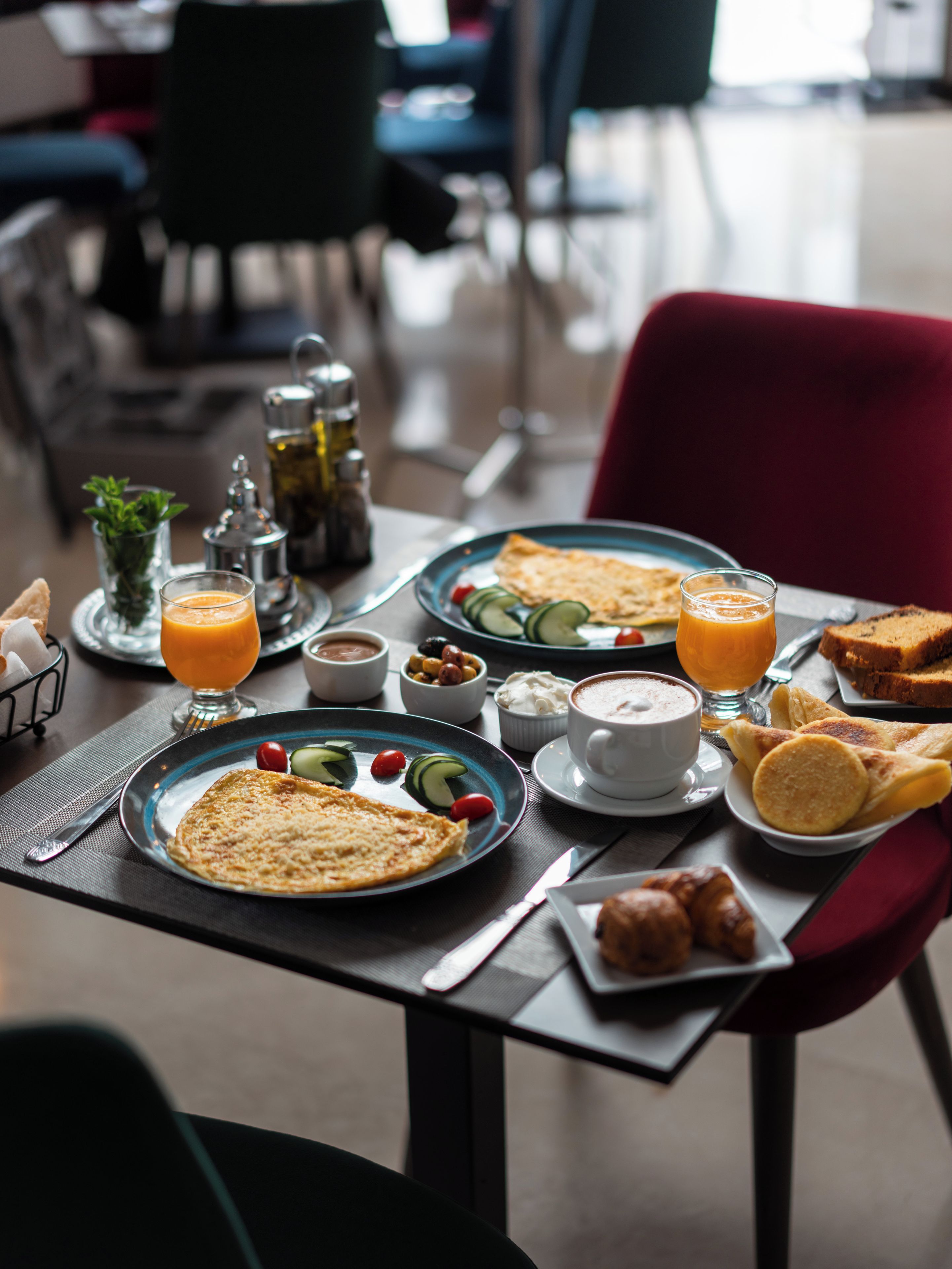 Mesa posta para o café da manhã, com pratos de comida, bebidas e acompanhamentos.