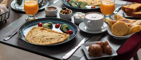 Una escena de desayuno con platos de comida, bebidas y salsas sobre una mesa.