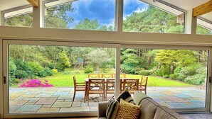 A modern interior with a large sliding glass door leading to an outdoor patio area. - Spacious Stylish Forest Escape | Kids Outdoor Play (Saint Leonards)
