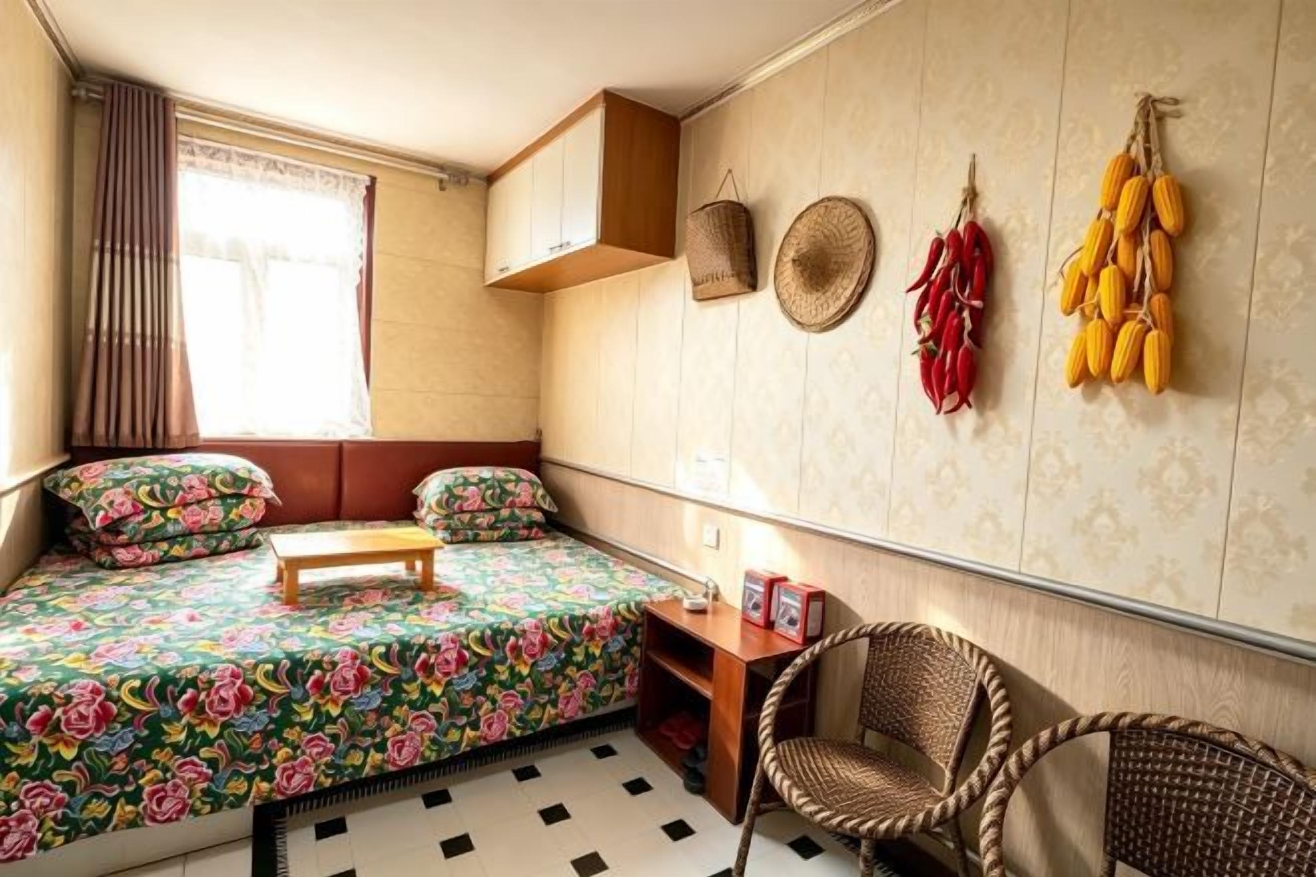 A compact room with a bed, a small table, a chair, and a window with curtains.
