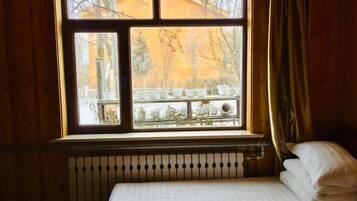 A room with a bed, a window with a view of outdoor furniture, and a radiator.