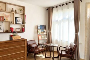 Una habitación con un escritorio de madera, dos sillones de cuero, una mesita redonda y una estantería con varios objetos.
