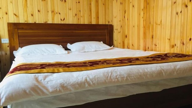 Un letto rifatto con lenzuola bianche e una coperta decorativa in una stanza con pannelli di legno.