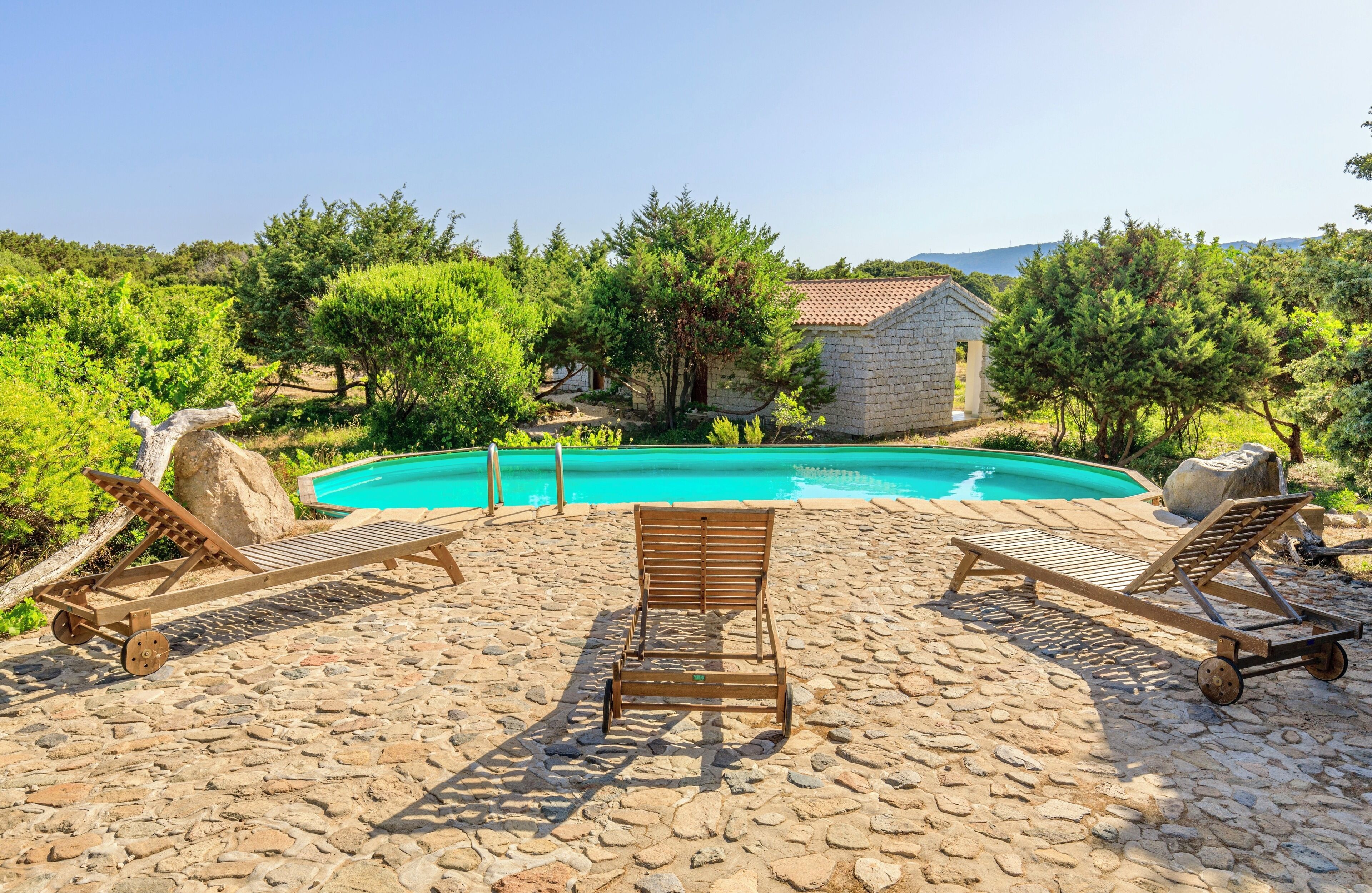 A pool area with lounge chairs and a stone patio.