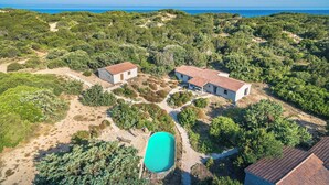 Vista aérea de una propiedad con dos edificios, piscina y vegetación circundante.