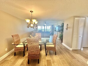 A dining area with wicker chairs, a glass table, and a chandelier. - Gulf and Bay Club C204 (Siesta Key)