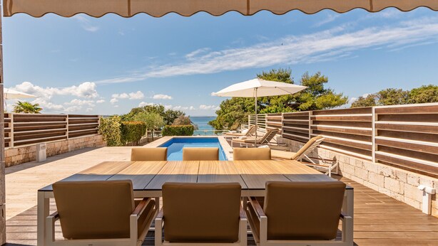 A wooden deck with a pool, lounge chairs, and an umbrella. - Villa Calla ZadarVillas (Petrcane)