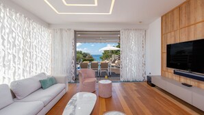 A modern living room with a sofa, two chairs, a coffee table, and a TV. - Villa Calla ZadarVillas (Petrcane)