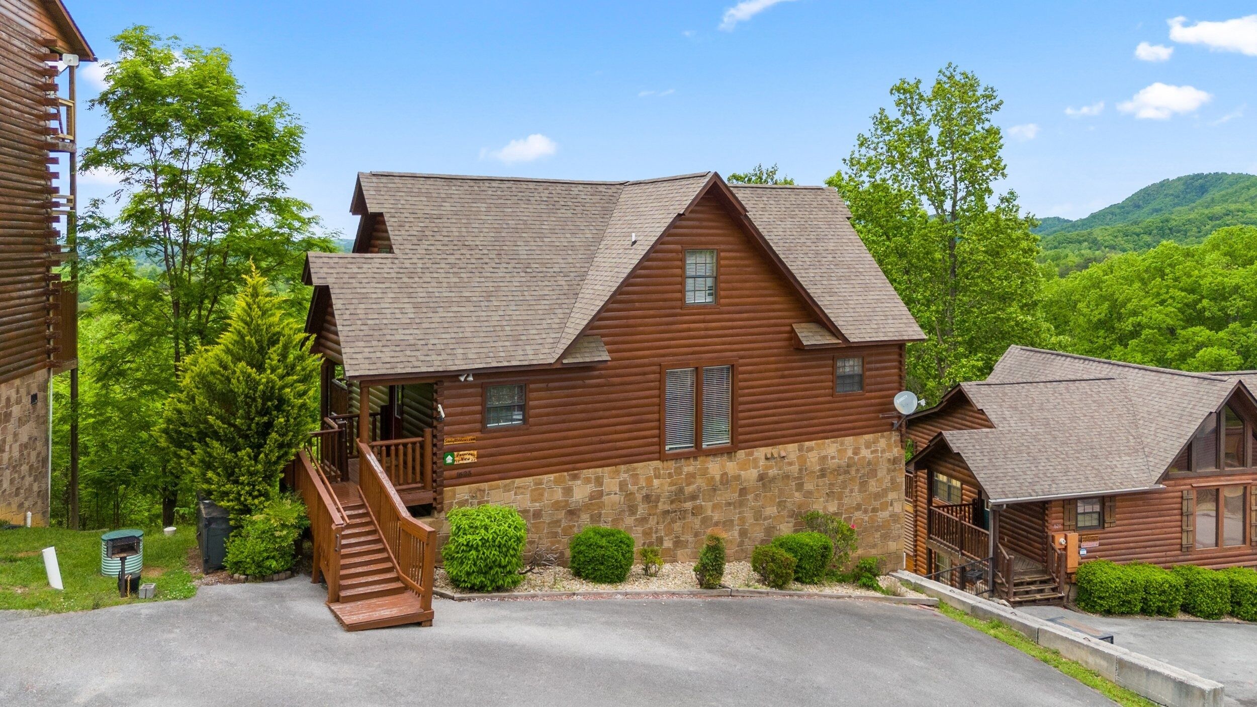 A log cabin with a stone foundation, a wooden porch, and a staircase leading to the entrance.