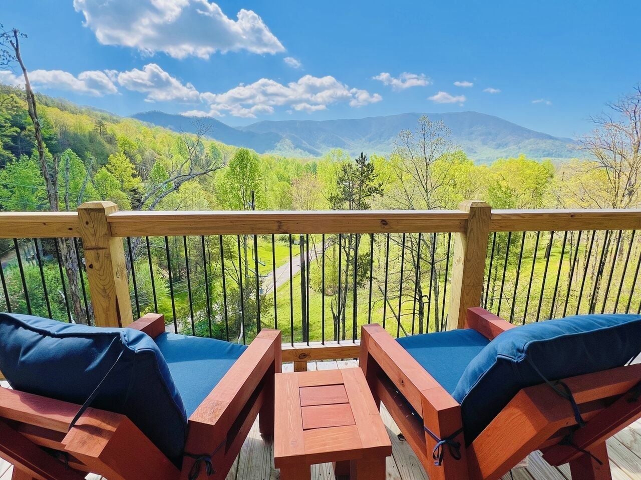 Une terrasse en bois avec deux chaises et une table, offrant une vue sur un paysage montagneux.