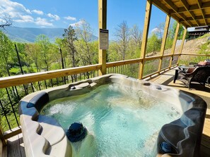 A hot tub on a wooden deck with a view of mountains and trees. - A Tyme To Chill 2 Bedroom Cabin by RedAwning (Sevierville)