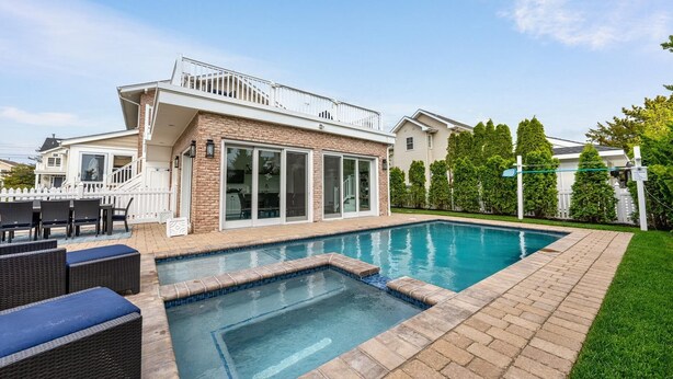 A residential backyard with a swimming pool, a covered patio, and a well-maintained lawn. - Seaside Serenity - Stone Harbor, NJ (Stone Harbor)