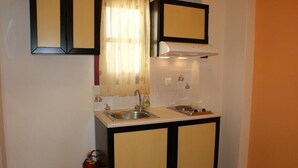A compact kitchen with a sink, a stove, and a fire extinguisher. - Verykokkos on the Beach (Naxos)