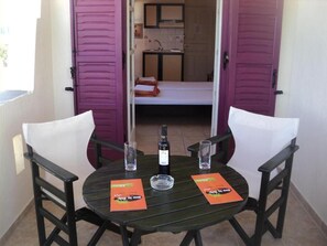 A small dining area with a round table, two chairs, a bottle of wine, and two glasses. - Verykokkos on the Beach (Naxos)