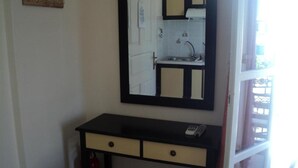 A small bathroom with a sink, mirror, and a single orange stool. - Verykokkos on the Beach (Naxos)