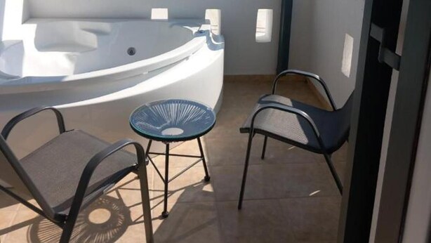 A balcony with a hot tub, two chairs, and a view of the sea. - Verykokkos on the Beach (Naxos)