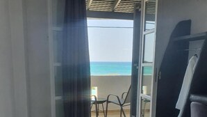 A room with a large bathtub, a balcony with a view of the ocean, and a chair. - Verykokkos on the Beach (Naxos)
