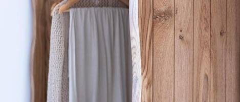A wooden door with a visible hinge and a wooden hanger with a garment.