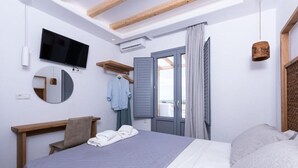 Ein Schlafzimmer mit Bett, Fernseher, Spiegel, Fenster mit Vorhängen und Holzboden.
