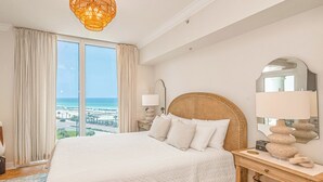 Un dormitorio amplio con una cama grande, vistas al océano y una cabecera de mimbre.