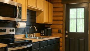 A kitchen with wooden cabinets, stainless steel appliances, and a black door.