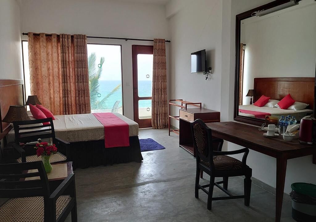A hotel room with a bed, desk, chair, and a large mirror.