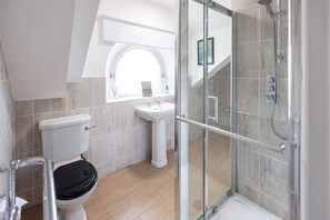 Une salle de bain moderne équipée de toilettes, d’un lavabo et d’une douche à parois de verre.