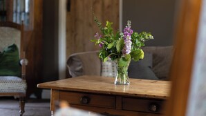 A wooden table with a clear glass vase containing flowers. - Lovely 2-bed Cottage in St Brides, Pembrokeshire (Haverfordwest)