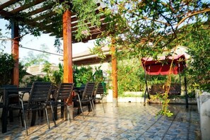 An outdoor patio with tables and chairs, a pergola, and a red umbrella. - Lane Cottage B&B (Zhuhai)