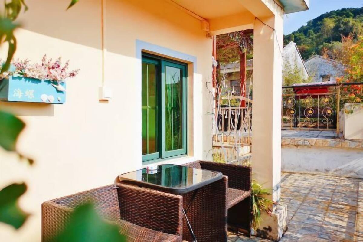 A balcony with wicker furniture and a glass table.