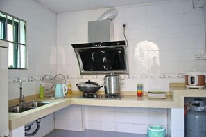 A kitchen with a stove, sink, and a window. - Lane Cottage B&B (Zhuhai)