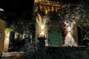 A building with a green door, surrounded by greenery and string lights. - Lane Cottage B&B (Zhuhai)