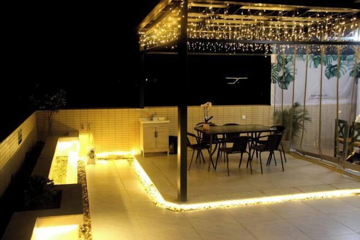 An outdoor dining area with a table and chairs, a tiled floor, and string lights.