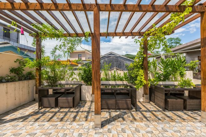 An outdoor patio with a pergola, seating, and potted plants.