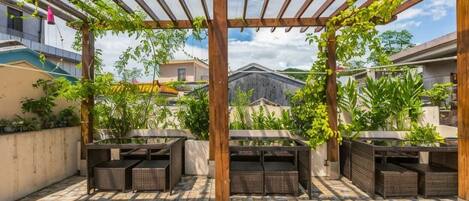 An outdoor patio with a pergola, seating, and potted plants.
