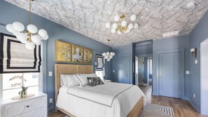 A bedroom with a large bed, a white dresser, and a ceiling with a leaf pattern. - Sip by the Pool - One bedroom, Pool, Beach Access (Pawleys Island)