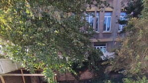 Un pequeño jardín vallado con césped artificial, un parque infantil de madera y una barandilla blanca.