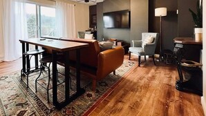 Una sala moderna con una mesa de comedor de madera, sillas de cuero, un sofá y un televisor montado en la pared.