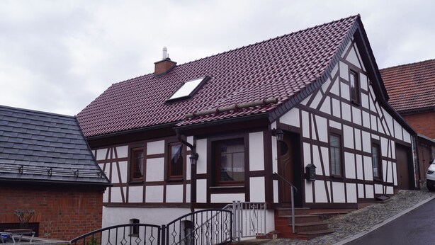 A traditional half-timbered house with a sloped roof, a small window, and a chimney. - Mitten im Thüringer Wald, Ferienhaus für die Ganze Familie (Steinbach-Hallenberg)