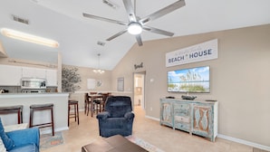 A spacious living area with a kitchen, a dining table, and a large TV.