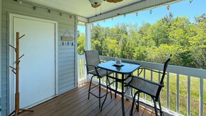 A covered porch with a table and chairs, a ceiling fan, and a view of trees.