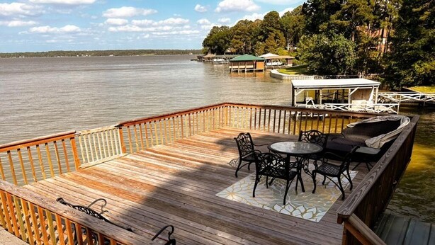 A wooden deck with outdoor furniture, a view of a lake, and docked boats. - One Acre Lakefront Home, Indian Hills Peninsula.  Pet friendly ! (Livingston)