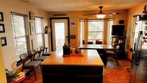 A kitchen with a central island, wooden chairs, a refrigerator, and a ceiling fan. - One Acre Lakefront Home, Indian Hills Peninsula.  Pet friendly ! (Livingston)