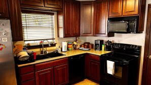 A kitchen with wooden cabinets, a stainless steel refrigerator, a microwave, a stove, and a sink. - One Acre Lakefront Home, Indian Hills Peninsula.  Pet friendly ! (Livingston)
