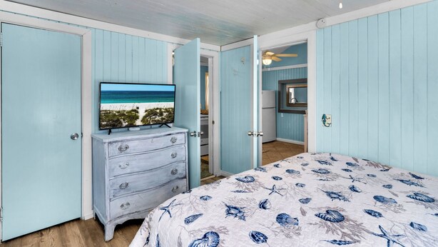 A bedroom with a bed, dresser, and television displaying a beach scene.