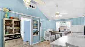 A kitchen with blue walls, white cabinets, a white stove, and a white refrigerator.