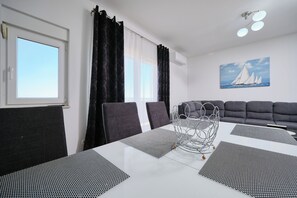 A modern dining area with a white table, black and white patterned placemats, and a metal sculpture centerpiece. - Villa Radun (Kastela)