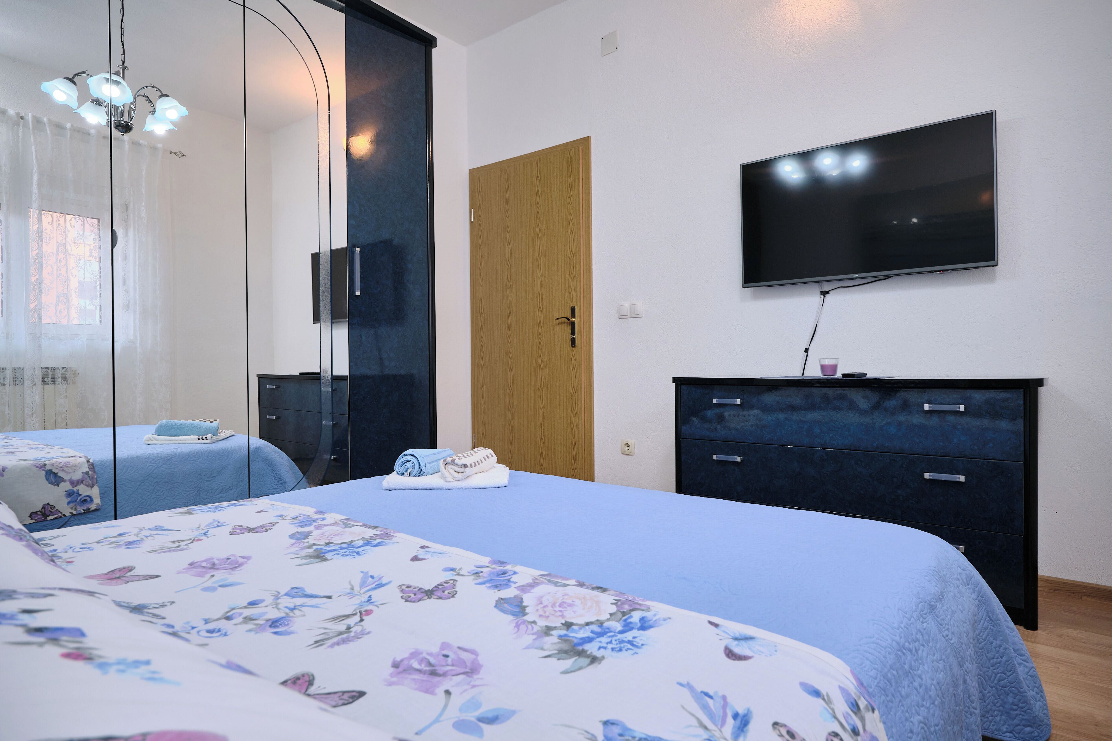 Ein Schlafzimmer mit Bett, Fernseher, Kommode und Tür.