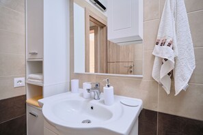 A bathroom with a white sink, mirror, and towel rack. - Villa Radun (Kastela)